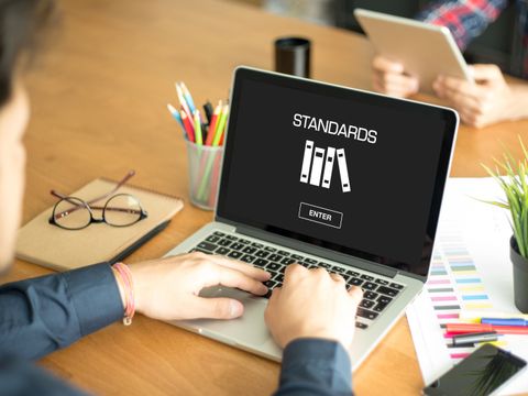 Hände am Laptop. Auf dem Bildschirm stehen die Worte Standards und Enter